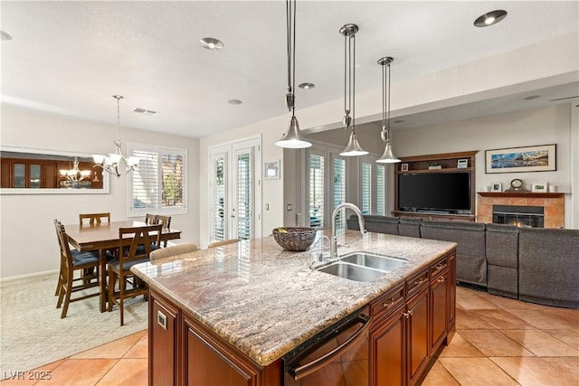 kitchen with sink, hanging light fixtures, light tile patterned floors, dishwasher, and an island with sink