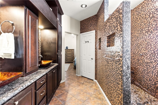 bathroom with tile patterned flooring, vanity, tiled shower, and tile walls