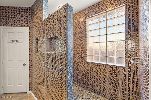 bathroom featuring plenty of natural light, tile patterned floors, and tiled shower