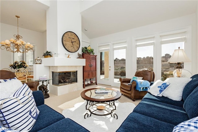 living room with a tiled fireplace, a notable chandelier, and high vaulted ceiling