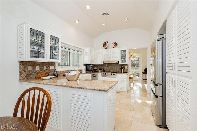 kitchen featuring lofted ceiling, white cabinetry, backsplash, stainless steel appliances, and kitchen peninsula