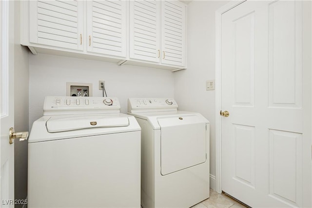 clothes washing area featuring light tile patterned floors, cabinets, and washing machine and clothes dryer