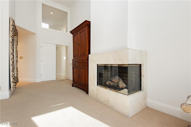 living room featuring light carpet, a tile fireplace, and a high ceiling