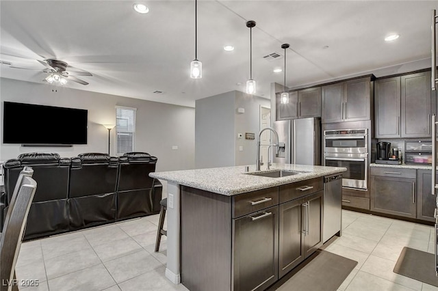 kitchen featuring an island with sink, pendant lighting, a breakfast bar area, and dark brown cabinetry