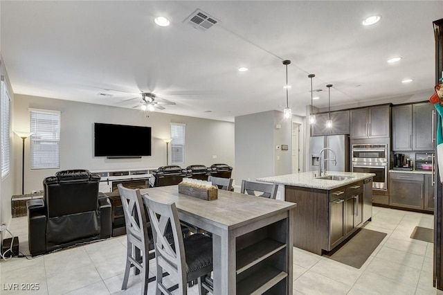 kitchen with dark brown cabinetry, appliances with stainless steel finishes, sink, and a kitchen island with sink