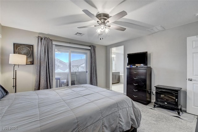 bedroom featuring ensuite bath, ceiling fan, access to exterior, light carpet, and a wood stove