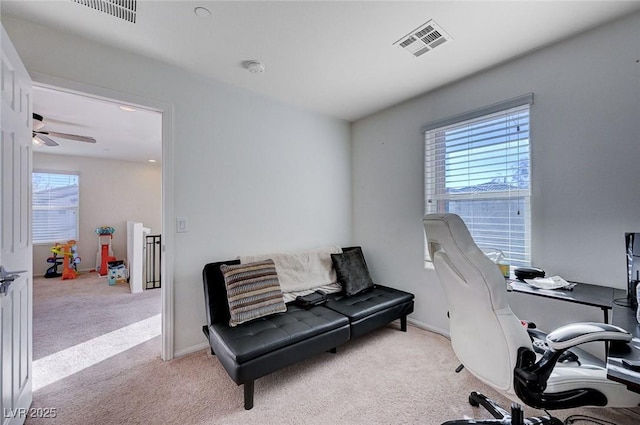 office space with a wealth of natural light, light colored carpet, and ceiling fan