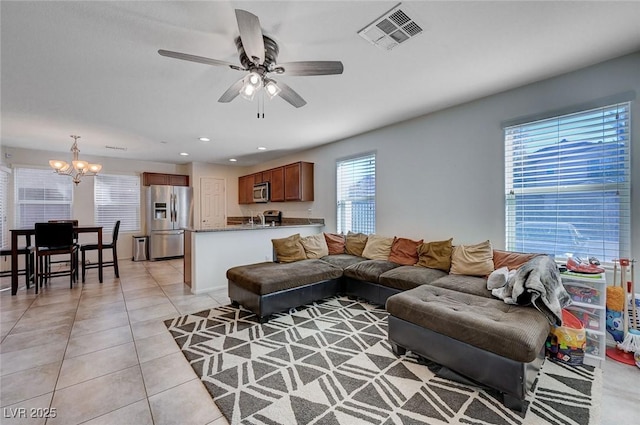 living room featuring light tile patterned flooring and ceiling fan with notable chandelier