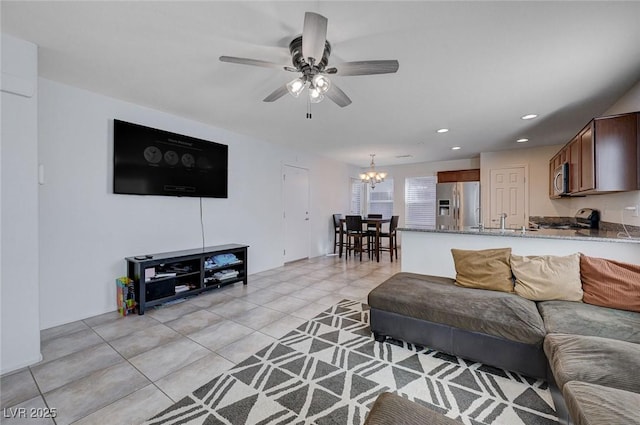 tiled living room featuring ceiling fan with notable chandelier