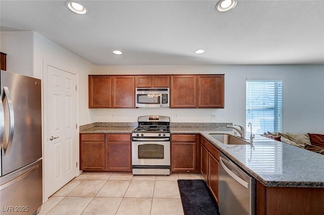 kitchen with stainless steel appliances, sink, light tile patterned floors, and kitchen peninsula