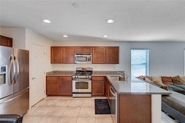 kitchen with light tile patterned flooring, appliances with stainless steel finishes, sink, light stone counters, and kitchen peninsula