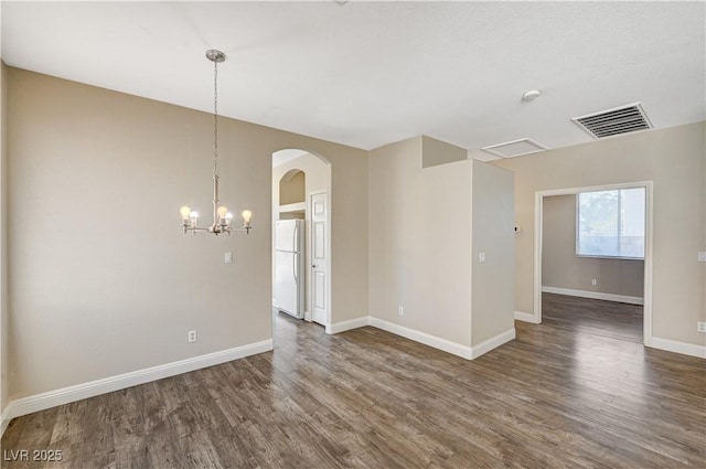 spare room with dark hardwood / wood-style floors and a chandelier