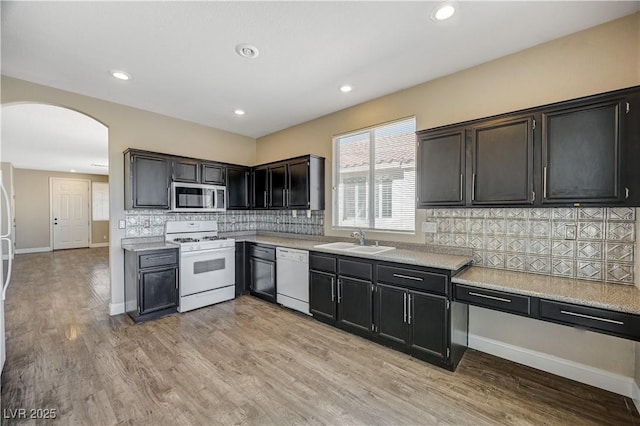 kitchen with light hardwood / wood-style floors, sink, white appliances, and decorative backsplash