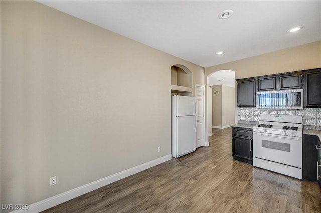 kitchen with backsplash, white appliances, and hardwood / wood-style floors