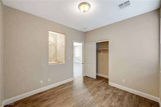 unfurnished bedroom with ensuite bath, light hardwood / wood-style flooring, and a closet