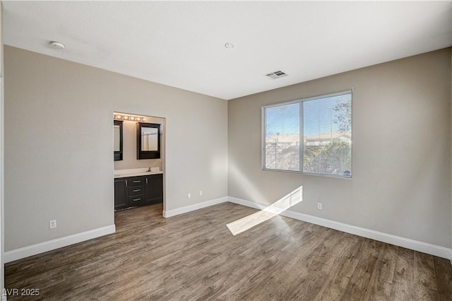 unfurnished bedroom with wood-type flooring, sink, and connected bathroom