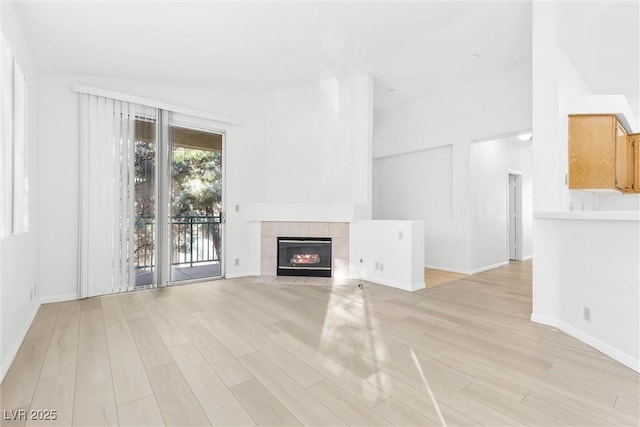 unfurnished living room featuring lofted ceiling, a fireplace, and light hardwood / wood-style floors