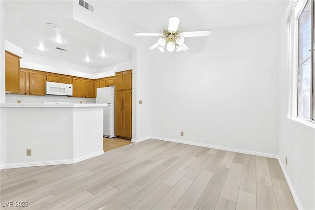 kitchen with ceiling fan, white appliances, kitchen peninsula, and light hardwood / wood-style flooring