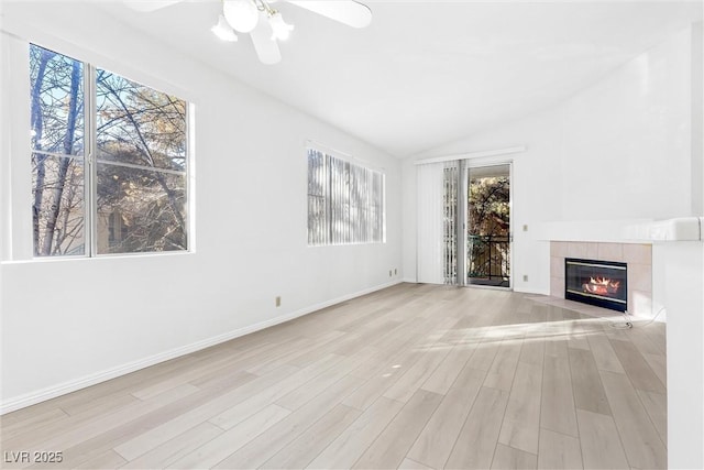 unfurnished living room with a tile fireplace, vaulted ceiling, ceiling fan, and light hardwood / wood-style flooring