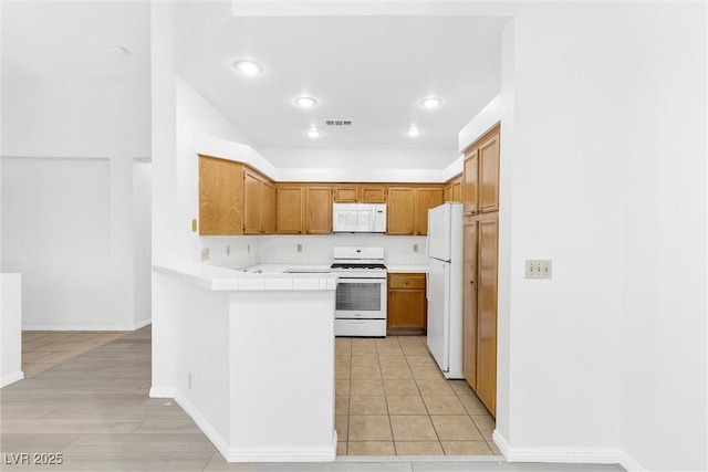 kitchen featuring light tile patterned floors, white appliances, and tile countertops