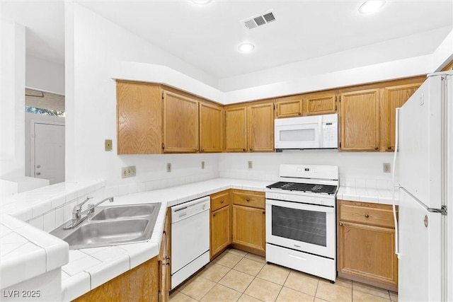 kitchen featuring light tile patterned flooring, sink, tile counters, kitchen peninsula, and white appliances