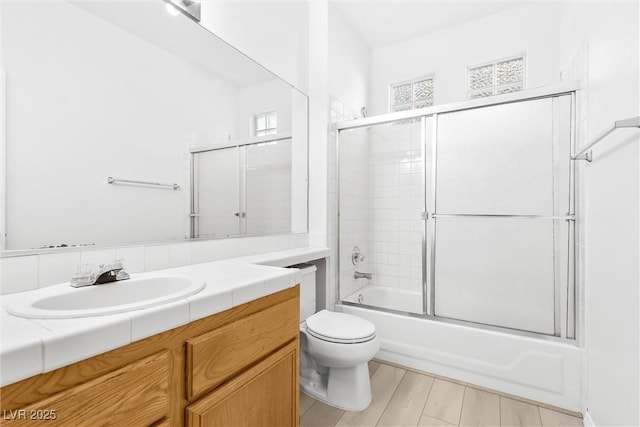 full bathroom featuring shower / bath combination with glass door, vanity, and toilet