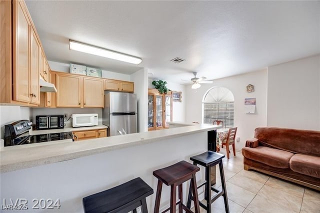 kitchen with stainless steel refrigerator, a breakfast bar area, light tile patterned floors, electric range, and kitchen peninsula