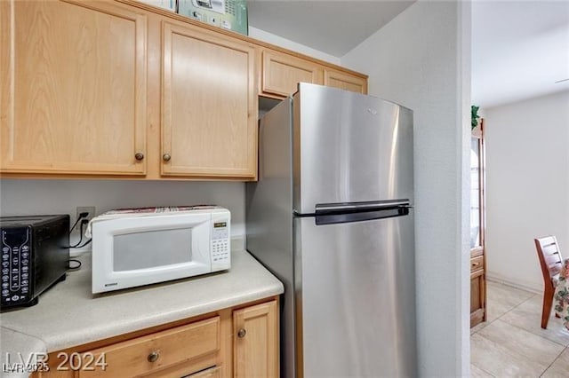 kitchen featuring light tile patterned floors, stainless steel fridge, and light brown cabinetry