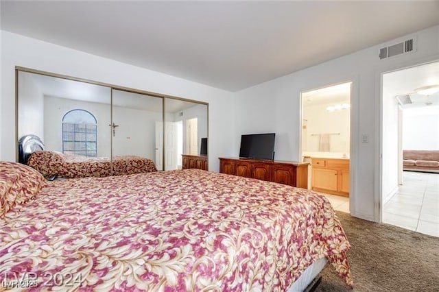 bedroom with ensuite bathroom, light carpet, and a closet