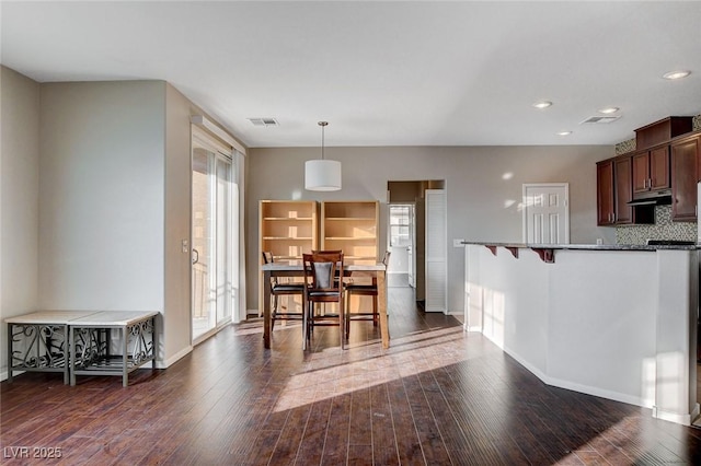 kitchen featuring pendant lighting, a wealth of natural light, backsplash, and a kitchen breakfast bar