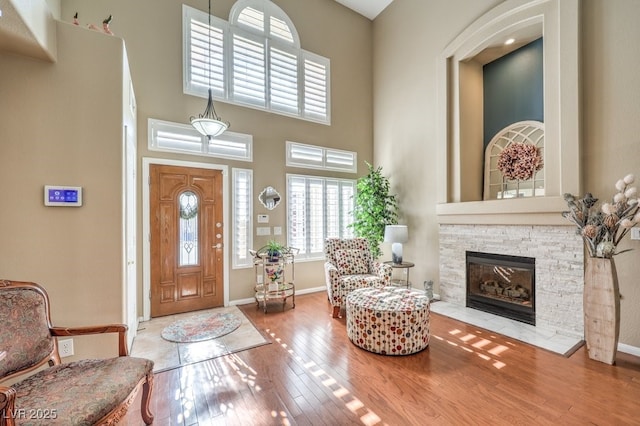 entrance foyer with wood-type flooring, a towering ceiling, and a fireplace