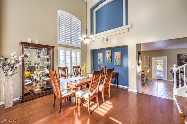 dining area with a towering ceiling, wood-type flooring, and a chandelier