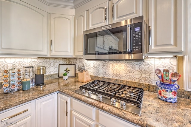 kitchen featuring appliances with stainless steel finishes, white cabinetry, backsplash, ornamental molding, and stone countertops