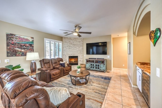 tiled living room with ceiling fan and a fireplace