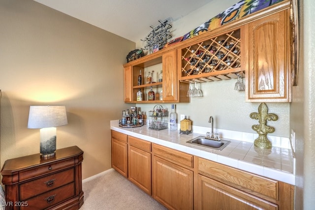 bar featuring light carpet, sink, and tile countertops