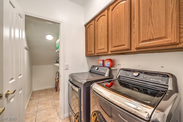 washroom featuring cabinets, light tile patterned floors, and washing machine and clothes dryer