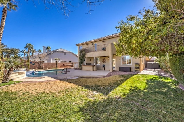 rear view of property featuring a balcony, a fenced in pool, a patio area, and a lawn