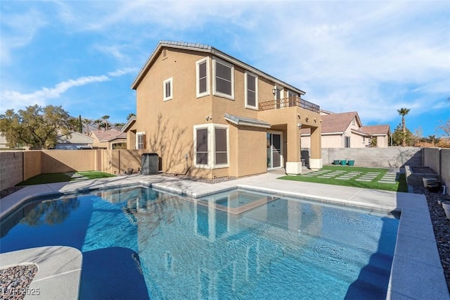 rear view of house featuring a fenced in pool, a balcony, and a patio area