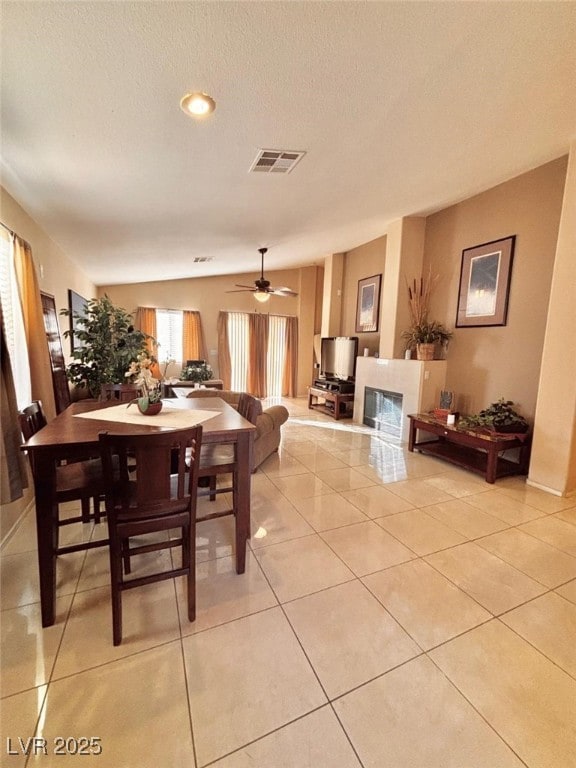 tiled dining room with ceiling fan and a textured ceiling