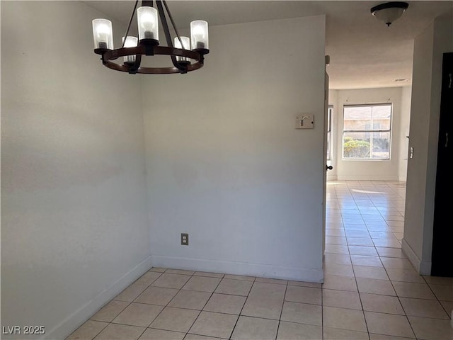 unfurnished room with light tile patterned flooring, baseboards, and a chandelier