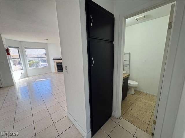 corridor with baseboards and light tile patterned flooring