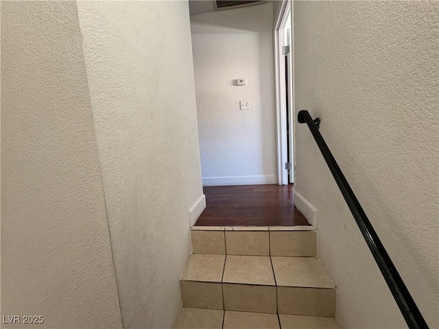 staircase featuring tile patterned flooring, visible vents, a textured wall, and baseboards