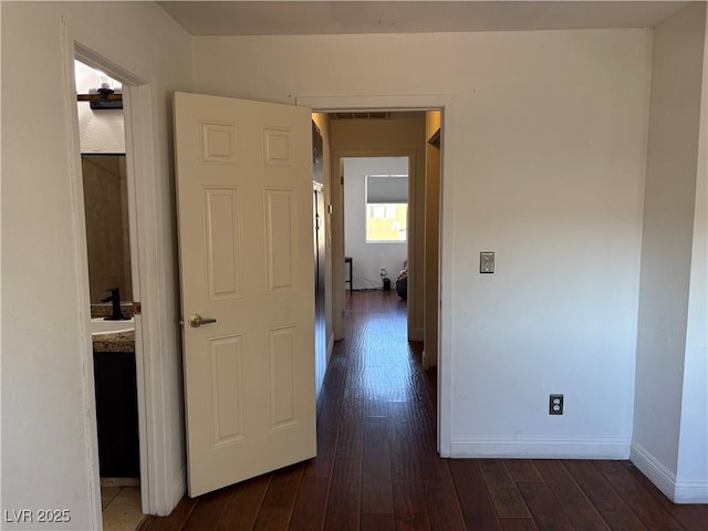 corridor featuring dark wood finished floors, visible vents, and baseboards