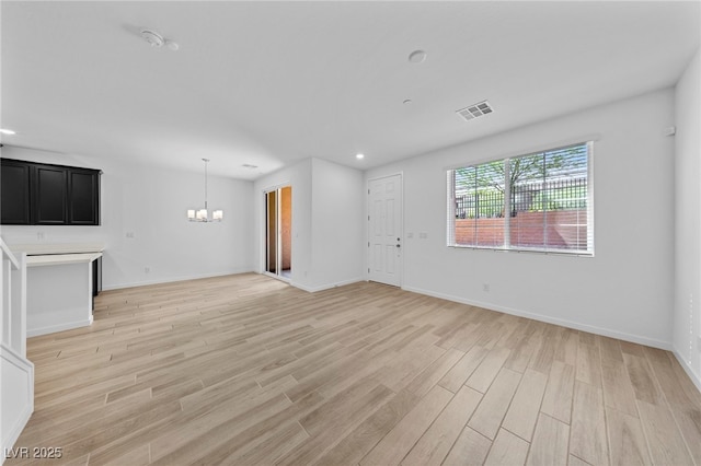 unfurnished living room with light hardwood / wood-style floors and a chandelier