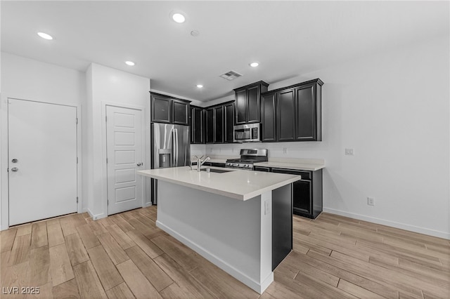 kitchen featuring stainless steel appliances, an island with sink, and sink