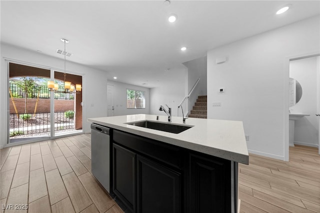 kitchen with sink, decorative light fixtures, a center island with sink, dishwasher, and a notable chandelier