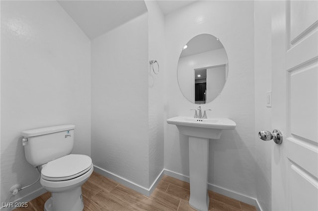 bathroom featuring hardwood / wood-style flooring, toilet, and vaulted ceiling