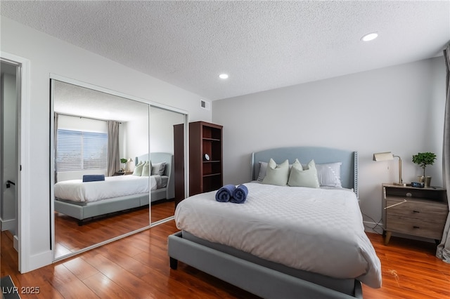 bedroom featuring wood-type flooring, a closet, and a textured ceiling