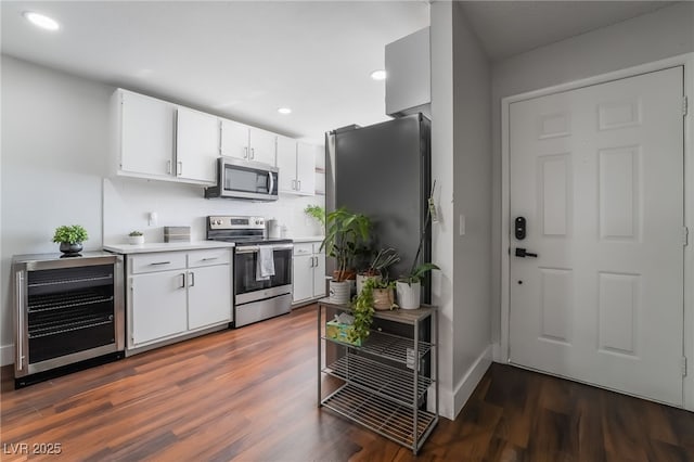 kitchen featuring dark wood-type flooring, white cabinetry, stainless steel appliances, beverage cooler, and backsplash