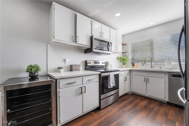 kitchen featuring appliances with stainless steel finishes, dark hardwood / wood-style floors, sink, wine cooler, and white cabinets